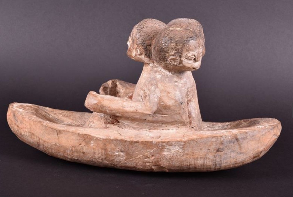 an early 20th century or earlier african wooden study of a three headed figure seated on a boat