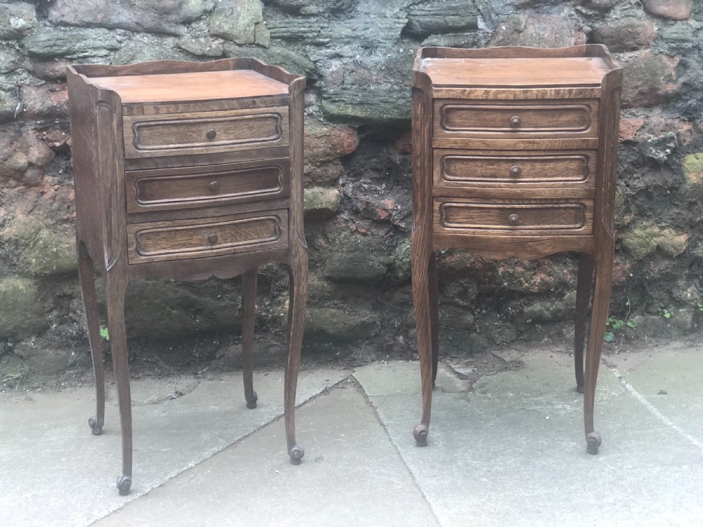 a pair of matching oak three drawer bedside chests