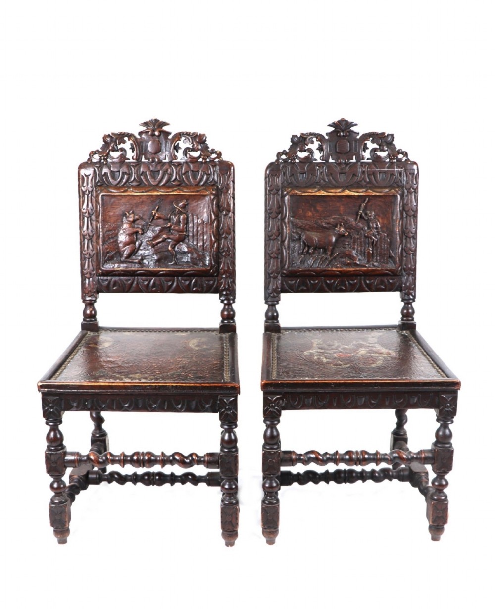 pair of black forest manner chairs with carved back showing a dancing bear