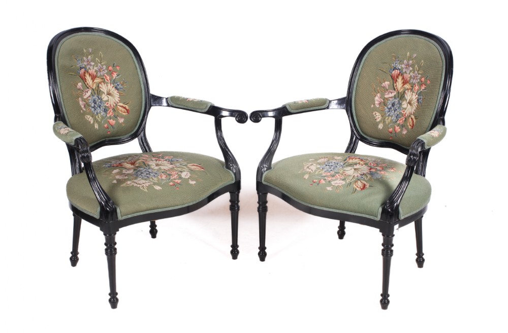 a pair of ebonised armchairs with embroidered tapestry covers